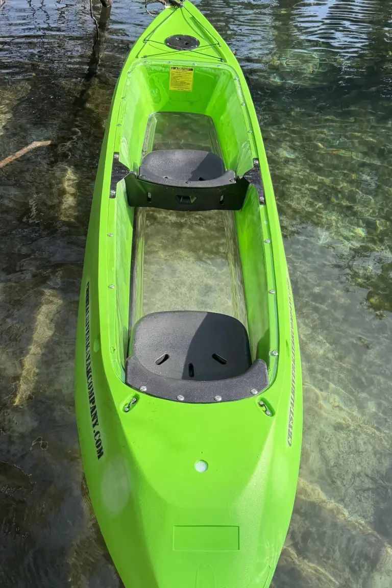 Overhead view of a bright green clear-bottom kayak in the water.