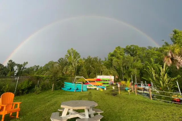 Rainbow arching above the kayak dock and colorful rental fleet.